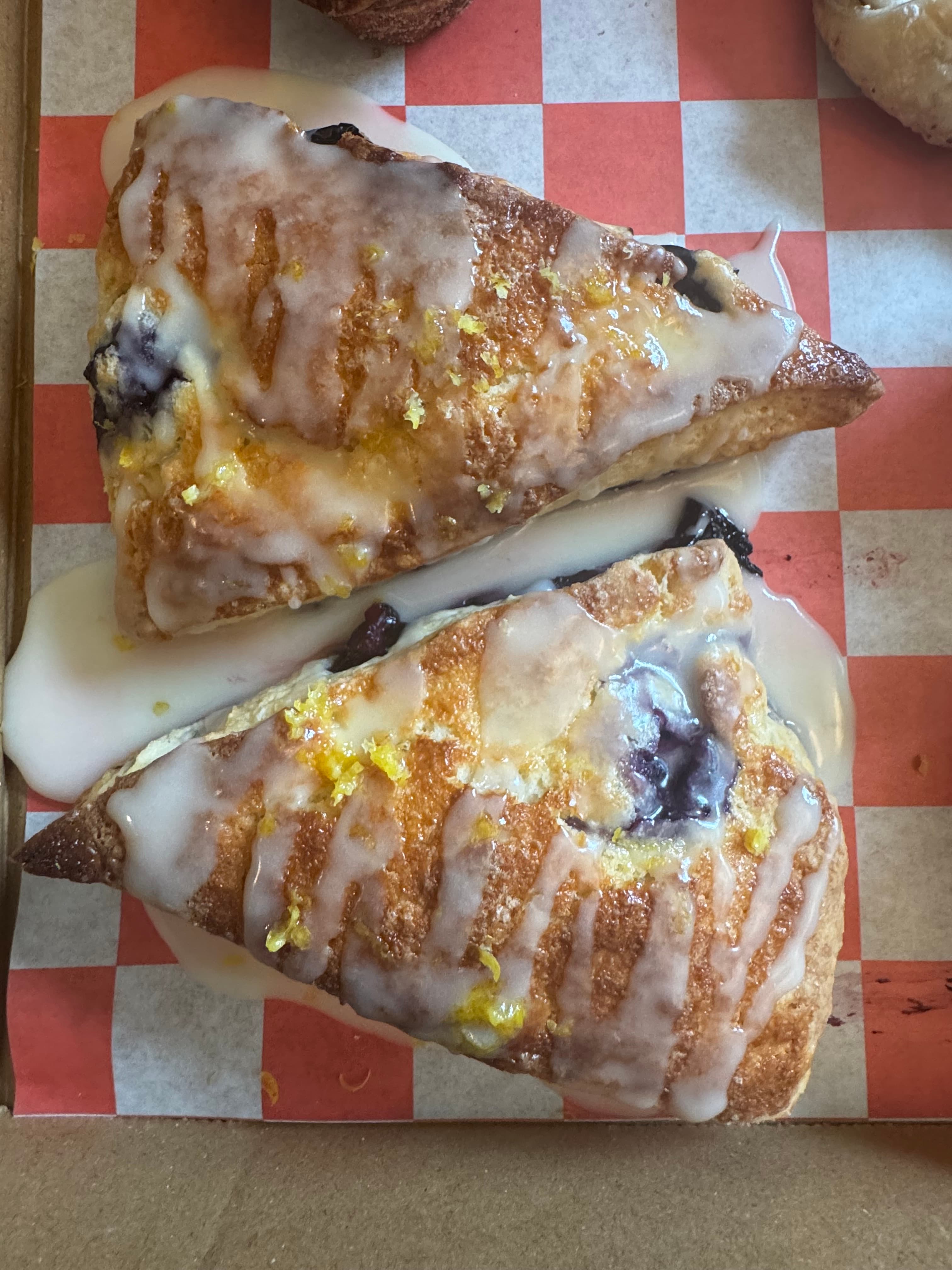 Two glazed blueberry lemon scones with visible berries