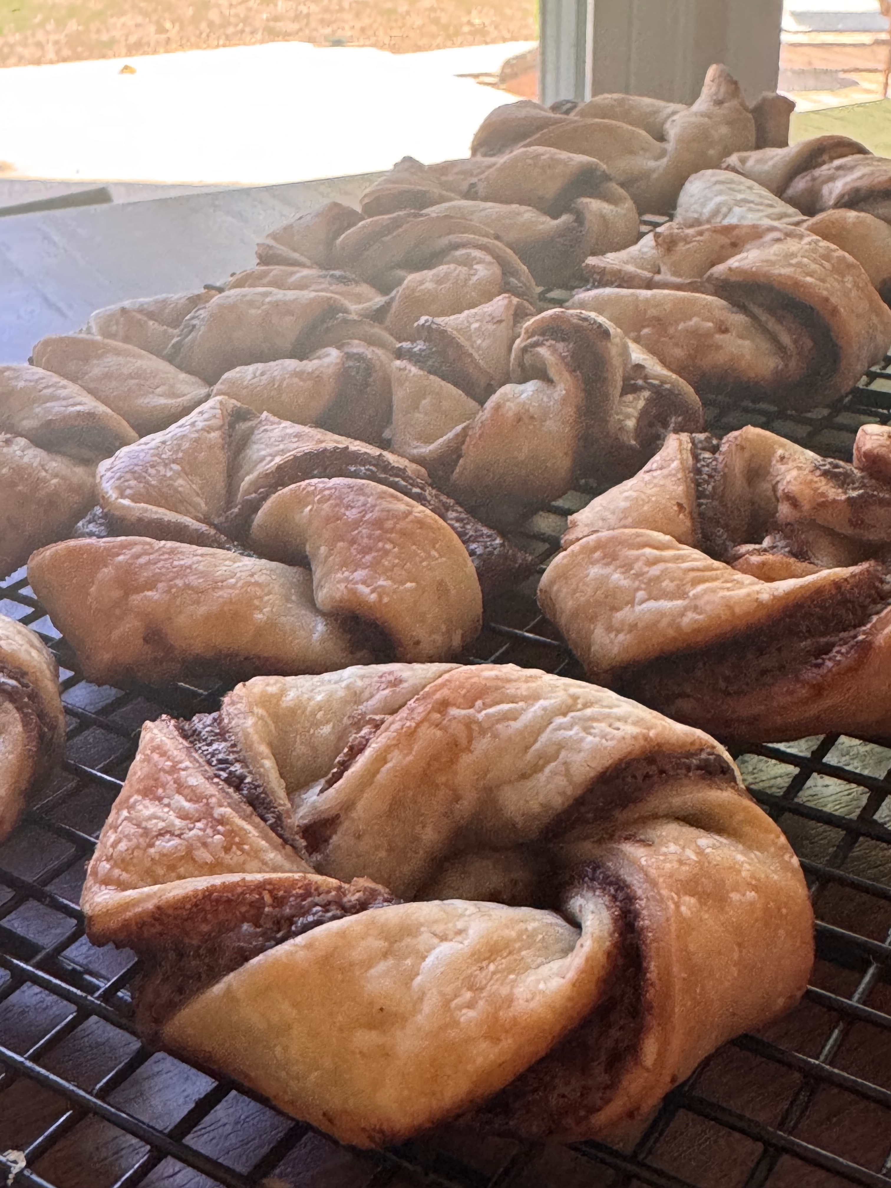 Multiple rows of hazelnut twisted pastries cooling
