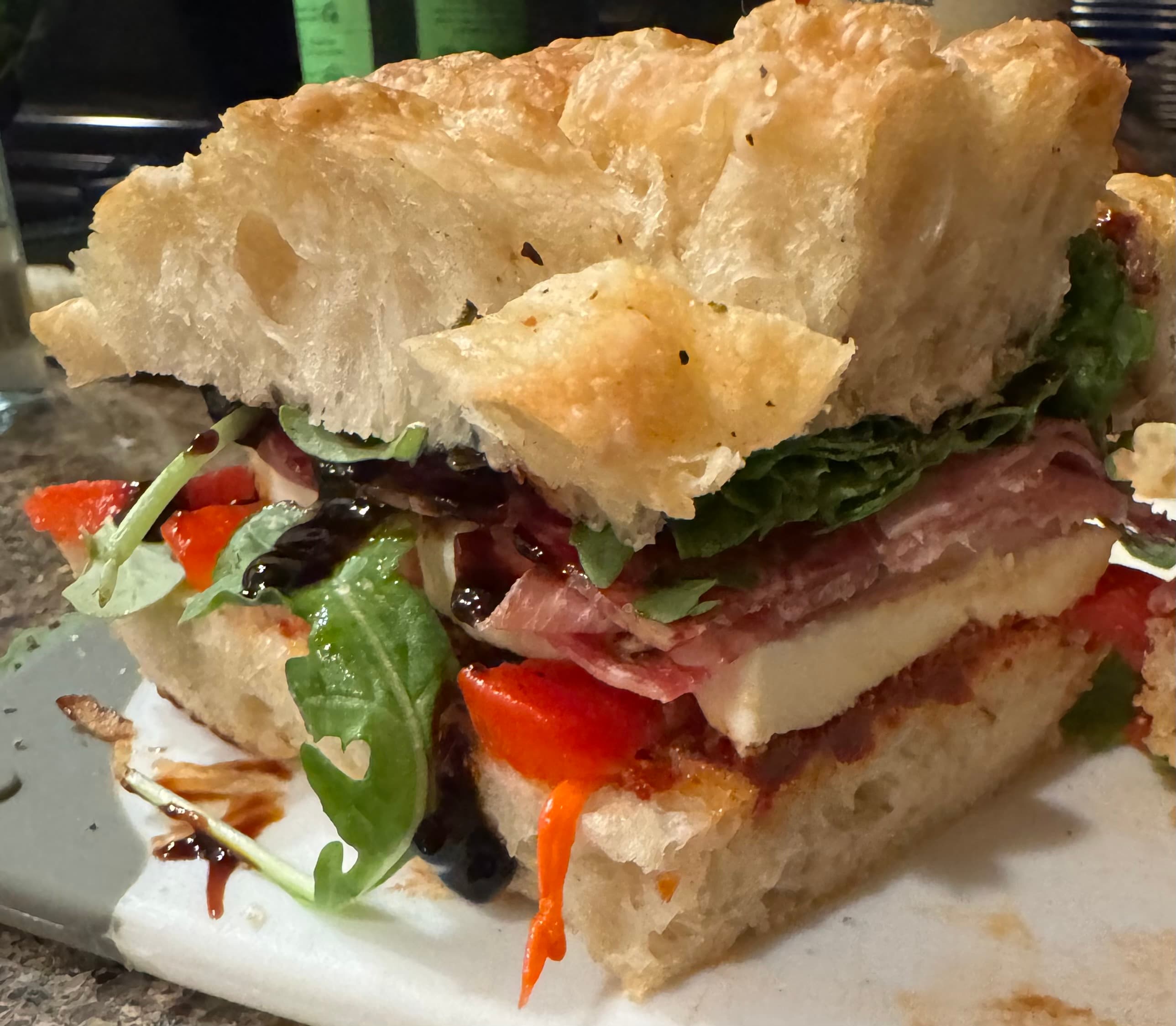 Artisan sandwich with prosciutto, mozzarella, and greens on focaccia